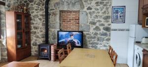 a kitchen with a table with a television and a stove at El Pontarron Apartamentos in La Franca