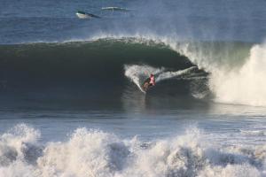 a man riding a wave on a surfboard in the ocean at Atlakamani Surf in Chirilagua