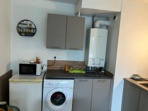 a kitchen with a washing machine and a microwave at Le 20 Joliot-Studio moderne in Mions