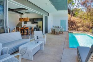 a patio with a pool and white furniture and a kitchen at Ocean View Tranquility 2BR with Pool in San Juanillo