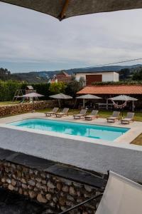 a swimming pool with lounge chairs and umbrellas at Casa da Ponte de Mucela in Vila Nova de Poiares