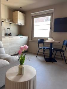 a living room with a couch and a table with flowers at Studio Strandkasteel, Free parking in Zandvoort +22 photos