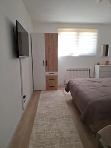 a bedroom with a bed and a flat screen tv at AMADA apartman in Vranješ