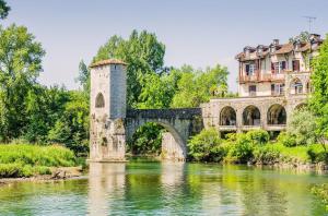 a bridge over a river in front of a building at Entre Galets in Sauveterre +10 photos