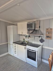 a kitchen with white cabinets and a stove top oven at Vedmyrastugan in Delsbo