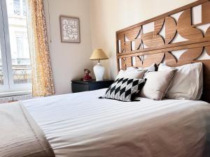 a bedroom with a large bed with white sheets and pillows at Les Appartements d Aristide Avallon in Avallon