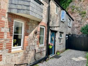 a brick house with a blue door and a fence at Mews Cottage in Torquay