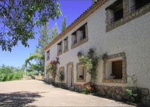 a white building with flowers on the side of it at El Molino de Iramala in Reolid