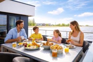 a family eating food at a table on a boat at Floatinghouse Boddenperle in Ribnitz-Damgarten