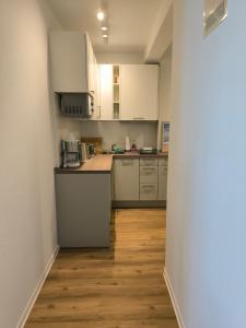 a kitchen with white cabinets and a wooden floor at Wind und Meer in Langeoog
