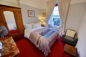 a bedroom with a bed and a chair and a window at Burnside Guest House in Ayr