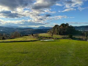 a field of green grass with mountains in the background at Casa do Cabo in Ribeira de Pena