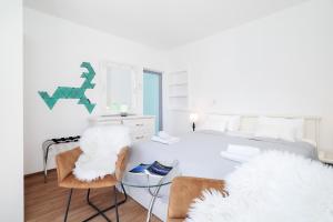 a white bedroom with a bed and two chairs at Apartments Bodlovic - ZF Hvar in Hvar