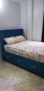 a bed with a blue frame with a floral blanket at Azille's Apt in Portsmouth