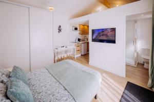 a white bedroom with a bed and a kitchen at L'extension - Studio in Aussonne