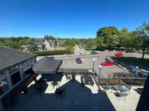 a patio with chairs and an umbrella and a parking lot at Ugie House in Keith