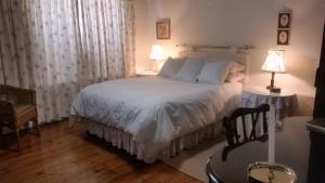 a bedroom with a white bed and a chair at Little Green World in Beaufort West