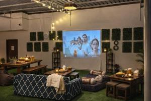 a living room with a large screen with a movie at Harvey's Brookefield-With Free Car Parking in Bangalore