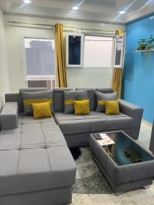 a living room with a gray couch and yellow pillows at Rufisque Dakar en face de la plage in Mbaw