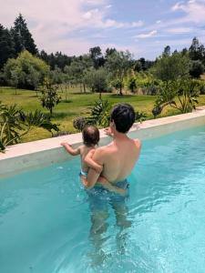 a man and a child in a swimming pool at A Casa do Olival in Mealhada
