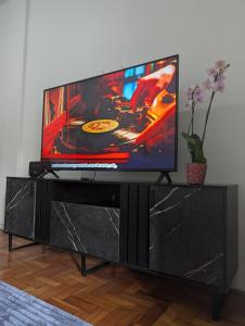 a flat screen tv sitting on a black entertainment center at Acomodaçao Ipanema in Rio de Janeiro