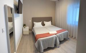 a bedroom with a bed and a television in it at Casa da Vila Guest House in Póvoa de Varzim +8 photos