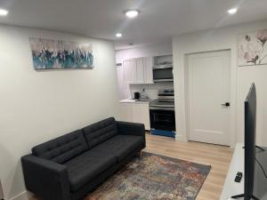 a living room with a black couch and a kitchen at Bournas Nest in Hammonds Plains