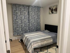 a bedroom with a bed and a blue curtain at Bournas Nest in Hammonds Plains