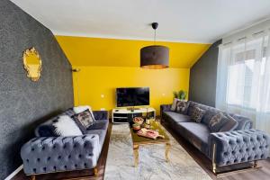 a living room with two couches and a yellow wall at Shalhome 1 Comfort at the gates of Strasbourg in Lingolsheim +19 photos