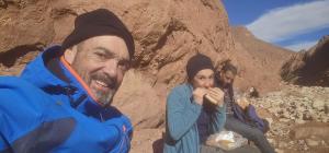 two men and a woman eating food in a desert at Maison du Bonheur berbère in Aït Ougliff +5 photos