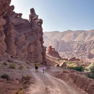 two people walking down a dirt road in the desert at Maison du Bonheur berbère in Aït Ougliff