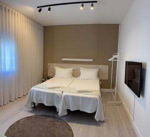 a bedroom with a large bed and a flat screen tv at Casa da Vila Guest House in Póvoa de Varzim