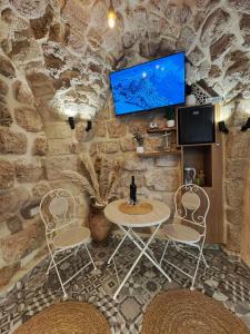 a stone wall with a table and chairs and a tv at Calamari Suite in Acre