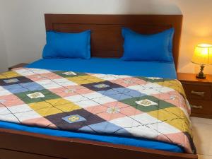 a bed with a blue pillow and a quilt on it at Rufisque Dakar en face de la plage in Mbaw