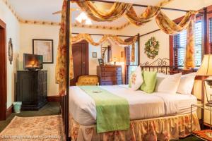 a bedroom with a canopy bed and a television at Cliff Cottage Inn, Downtown Bed & Breakfast in Eureka Springs