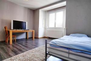 a bedroom with a bed and a desk with a television at Ferienwohnung Kaspar mit Parkplatz in Pforzheim