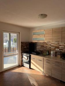 a kitchen with wooden cabinets and a television and a window at Cabana Piatra Buru in Buru