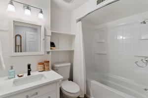 a white bathroom with a toilet and a sink and a tub at Pier Pointe #101 - 100 Floyd Street, Unit 101 in Saint Simons Island +27 photos