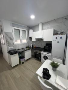 a kitchen with white cabinets and a table and a refrigerator at Apartamento en el centro vinaros in Vinarós