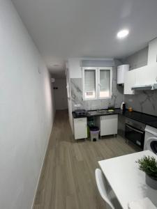a kitchen with white cabinets and a wooden floor at Apartamento en el centro vinaros in Vinarós