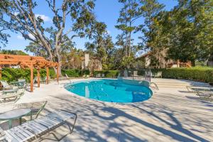 a swimming pool with chairs and a pergola at Harbour Oaks, Unit 419 in Saint Simons Island
