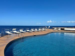 a swimming pool with chairs and the ocean in the background at Mare Infinito in Pantelleria