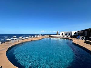 a swimming pool with chairs and the ocean in the background at Mare Infinito in Pantelleria