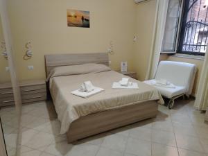 a bedroom with a bed and a chair with towels on it at Sicilian Room in Catania