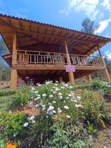 a wooden pavilion in a garden with flowers at Cabaña Loto - Paipa in Paipa