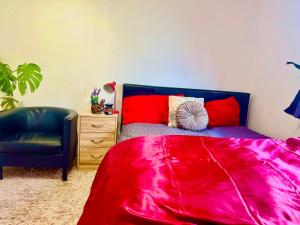 a bedroom with a red bed and a blue chair at Westcliff Cottage in Southend-on-Sea