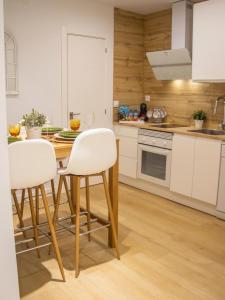 a kitchen with a wooden table and white chairs at Jerez Centro Alojamiento Boutique in Jerez de los Caballeros +7 photos
