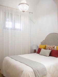 a bedroom with a large white bed with a chandelier at Jerez Centro Alojamiento Boutique in Jerez de los Caballeros