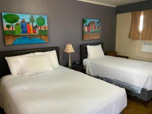 two beds in a hotel room with white sheets at The Triangle Motel in Alma