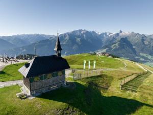 a church on a hill with mountains in the background at Berghotel Schmittenhöhe - 2000m in Zell am See